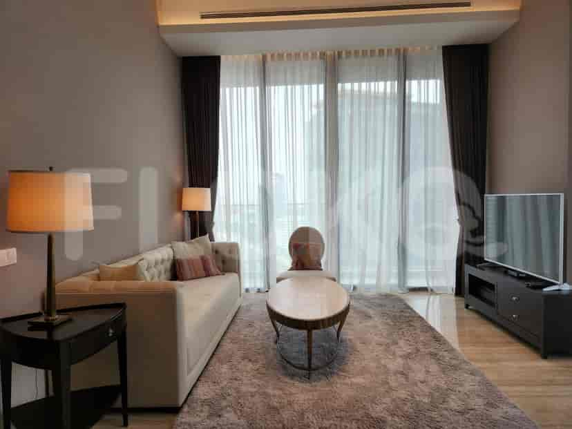 A luxury living room featuring a beige sofa, a low table, and a large window with sheer and dark curtains.