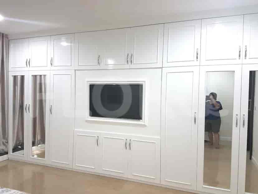 Spacious bedroom with a wall of white glossy closets and a large TV.