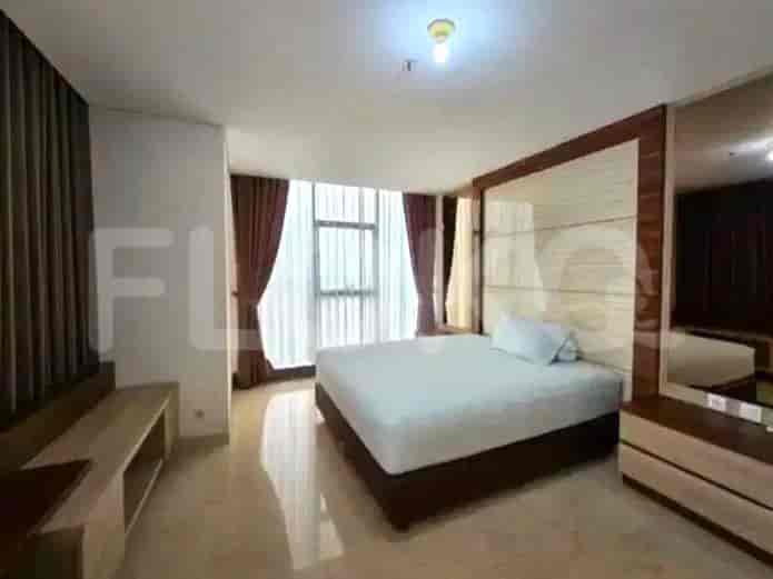 Bedroom with a bed, wooden panel headboard, and large windows.
