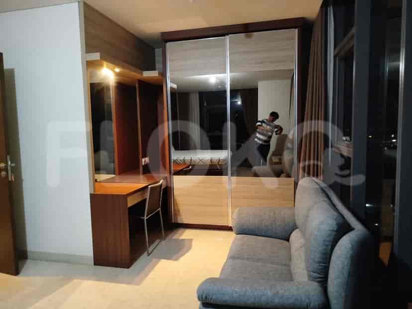 A modern living area featuring a sofa, built-in wardrobe with mirror doors, and a desk area.