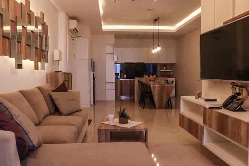 Modern living area with a beige sofa, open-plan kitchen, and a mounted TV.