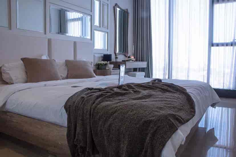 Bright bedroom with a large bed, floor-to-ceiling windows, and sheer curtains.