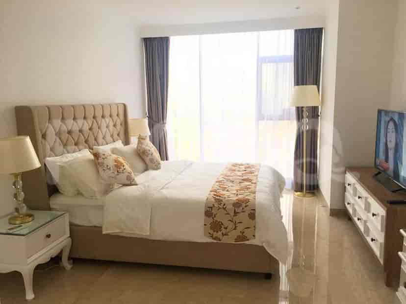 A bright bedroom featuring a large bed, bedside lamps, and a TV.