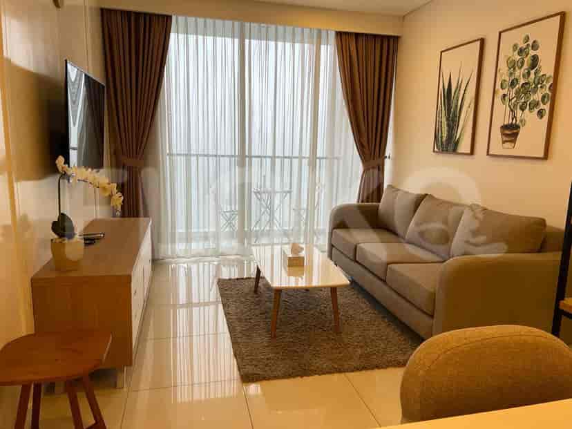 A modern living room with a gray sofa, TV, and large windows.