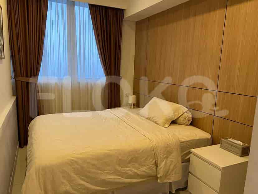 A bedroom with a bed, wooden paneling, and window with brown curtains.
