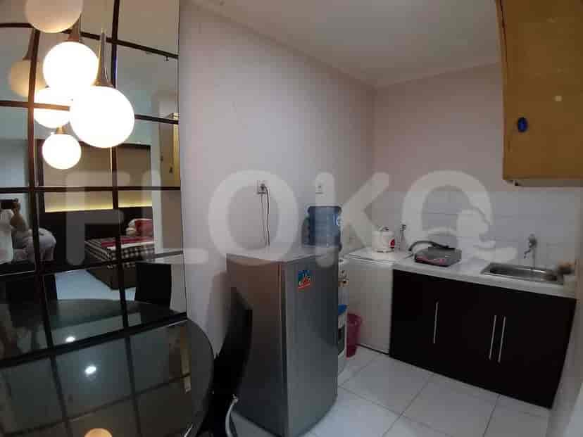 A small kitchen with a fridge, water dispenser, and basic appliances.