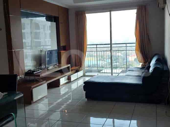 A modern living room featuring a dark grey L-shaped sofa, a wall-mounted TV, and a balcony with a city view.