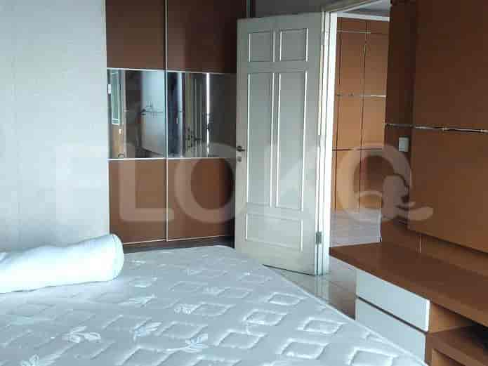 Close-up view of the bedroom, focusing on a double bed and wooden wardrobe.