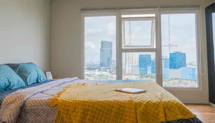 Another view of the bedroom, with the bed, and large windows offering a city view.