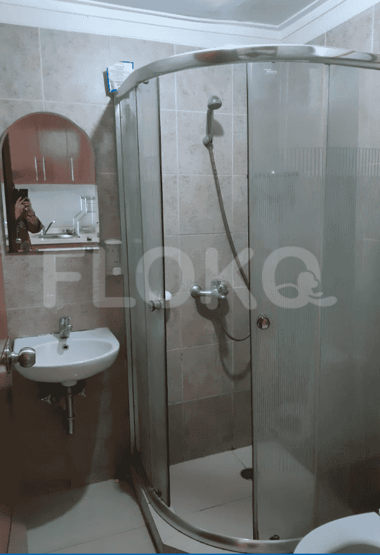 Kamar mandi dengan pancuran dan wastafel.