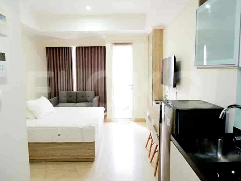 A studio apartment with a bed, a TV, and a sofa.