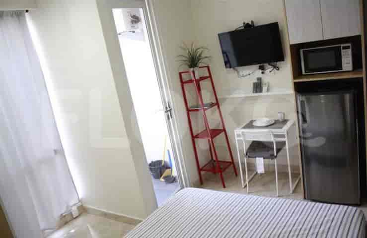 A combined living and kitchenette space with a table, ladder shelf, and access to a balcony.
