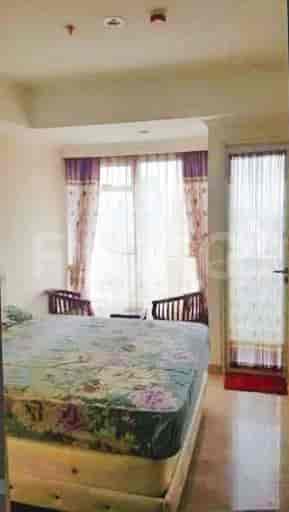 A bedroom featuring a bed with a floral patterned cover, curtains, and wooden chairs.