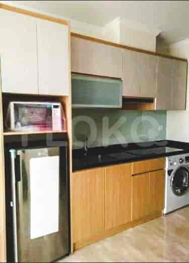 A modern kitchen with wooden cabinets, a stainless steel refrigerator, and a washing machine.
