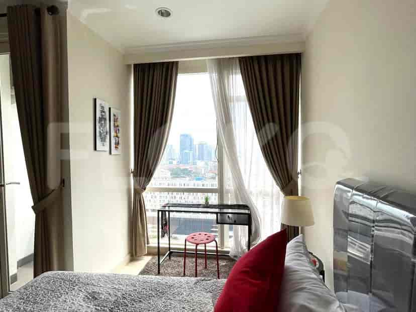 A bedroom with a bed by the window, a desk, and city views.