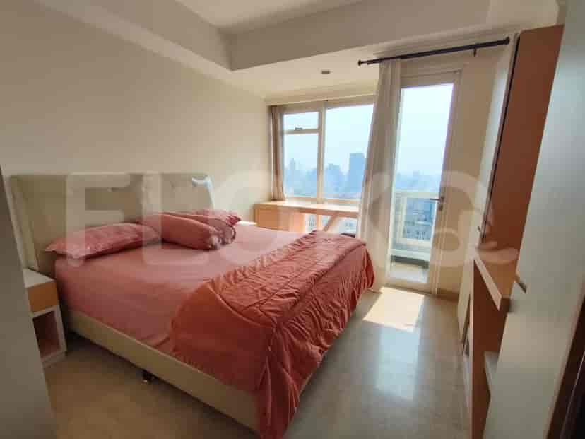 A modern bedroom with a bed, a nightstand, and a view of the city through the window.