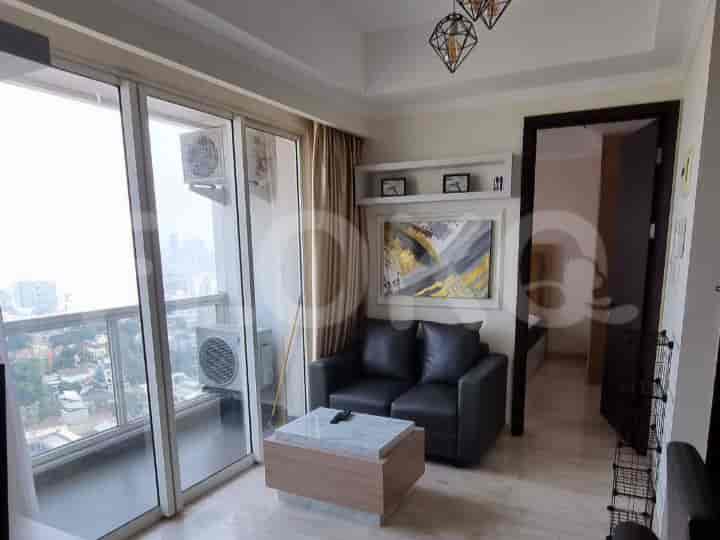 A modern living room with a black sofa, a coffee table, and a view of the city through a large glass door.