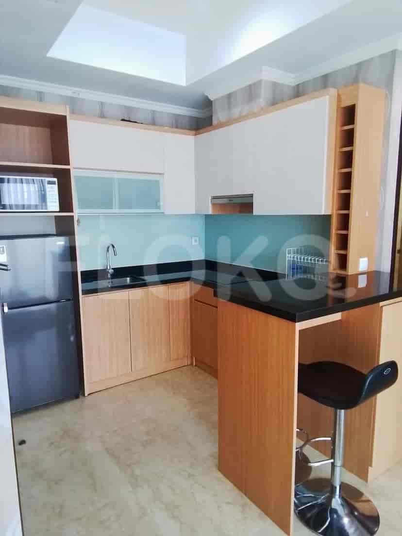 A modern kitchen featuring wooden cabinets, black countertops, and a breakfast bar.