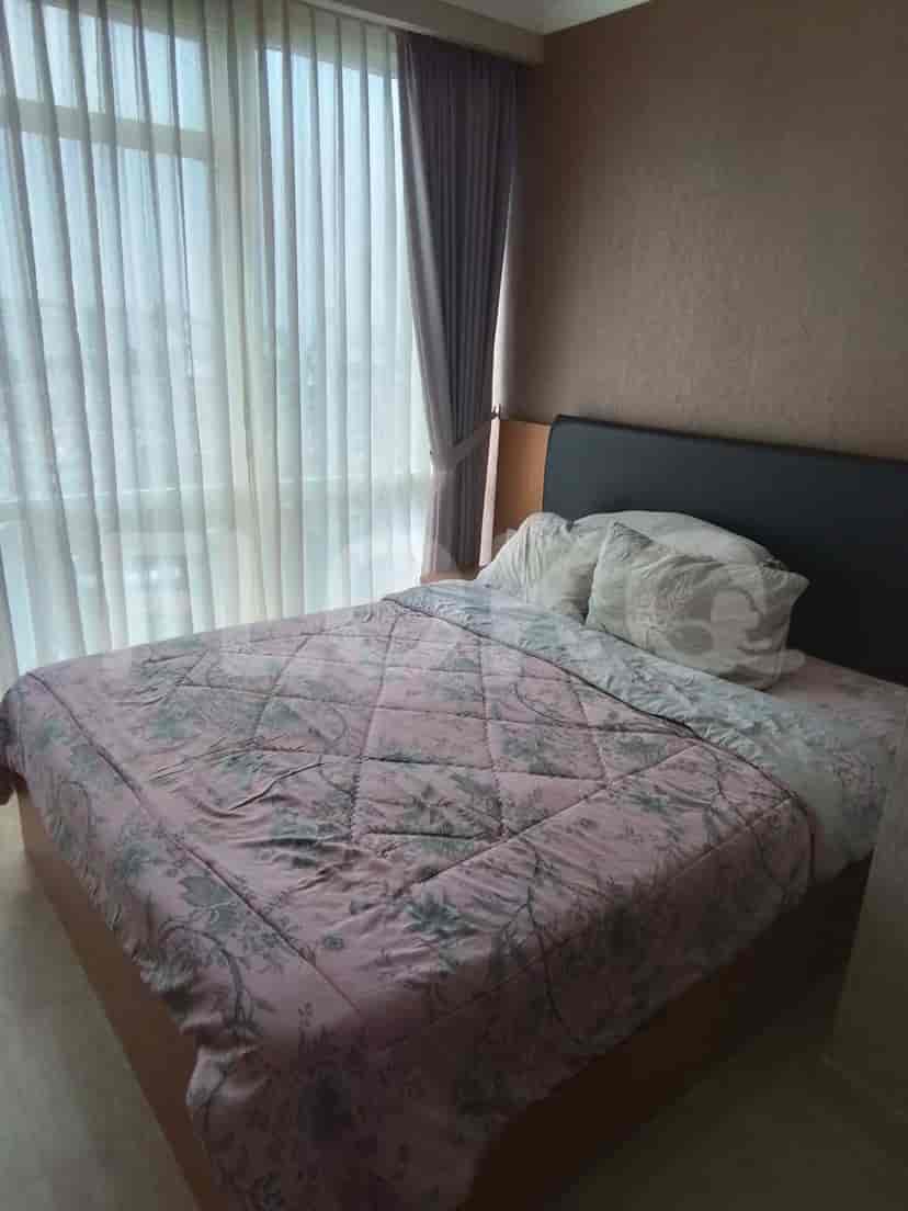 A bedroom with a bed, large windows, and soft curtains.