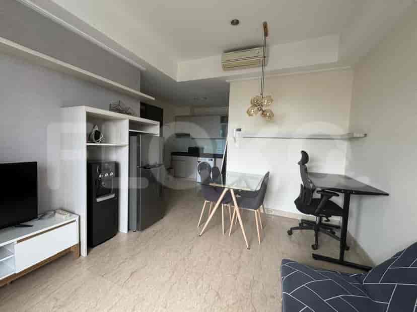 A combined kitchen and living space, featuring a refrigerator, dining area, and sofa.