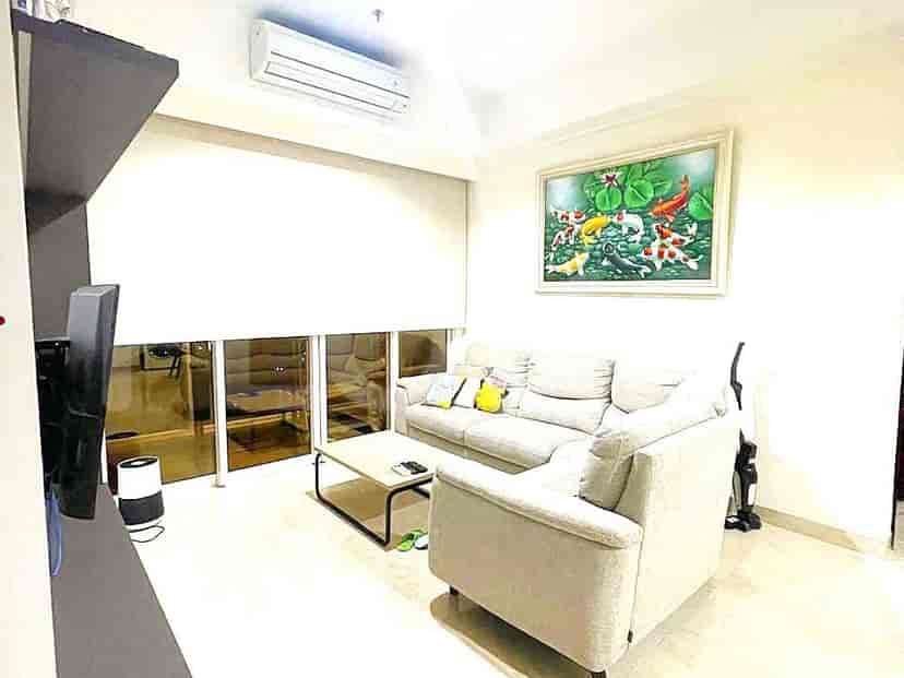 Ruang tamu dengan sofa abu-abu, meja kopi, dan karya seni.