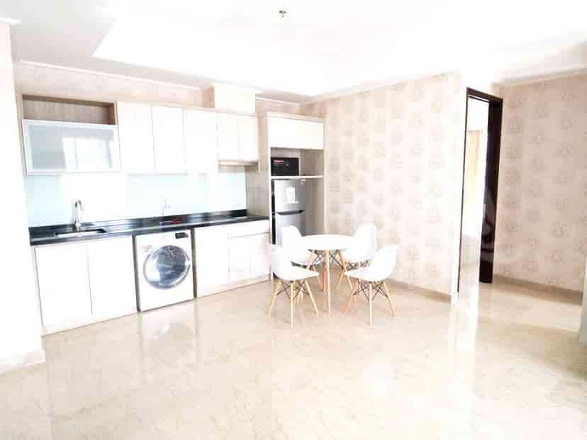 Area dapur modern dengan lemari putih, meja makan bundar, dan ruang tamu gabungan.