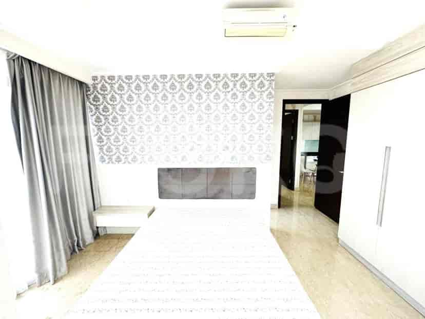 Kamar tidur modern dengan tempat tidur besar, meja samping tempat tidur, dan lemari.