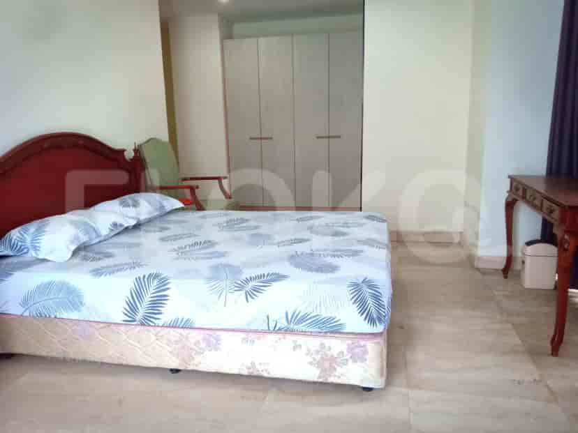 A bedroom with a bed, closet, and a chair.