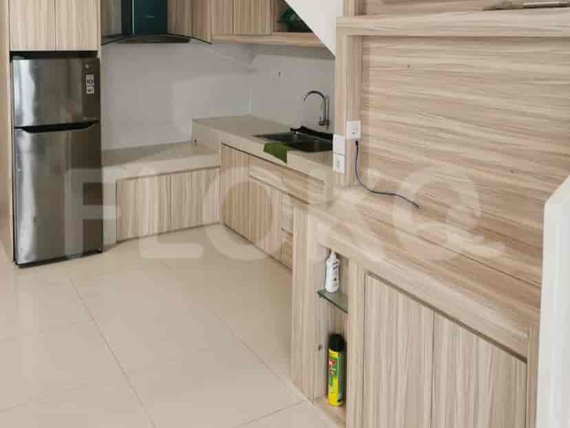 The kitchen, featuring wooden cabinetry, a stainless steel refrigerator, and a cooking hood.
