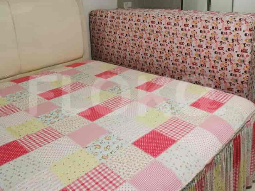Bedroom with a bed, patterned bedspread, and a headboard cover.