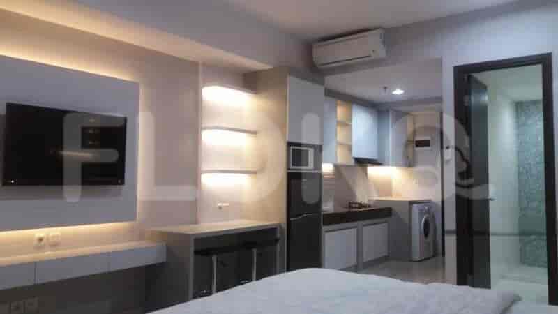 A modern studio apartment with a living area featuring a bed, a kitchenette equipped with appliances, and a small dining counter.