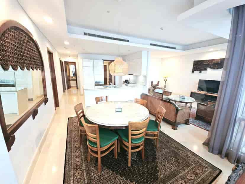 A dining area with a round table, chairs, and a large rug.