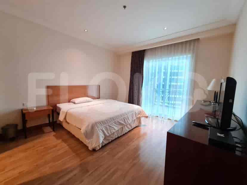 Bedroom with a queen bed, wooden flooring, and dark curtains.