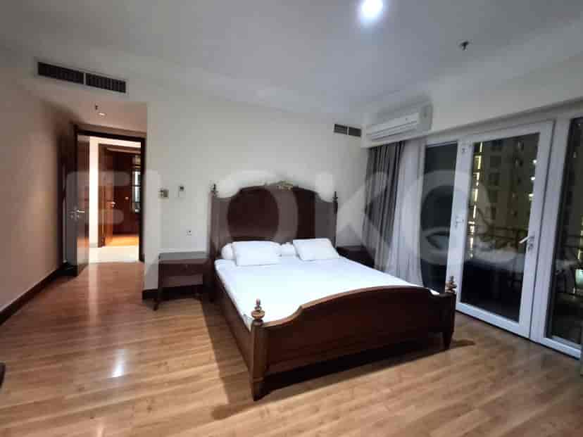 A master bedroom with a king-sized bed, a nightstand, and a door leading to another room.