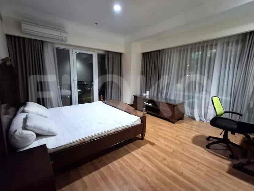A large bedroom with a king-sized bed, a TV, and a large window with curtains.
