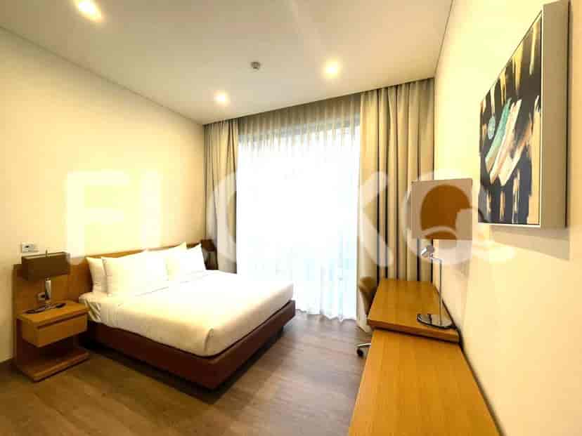 A spacious bedroom with a bed and a desk, featuring neutral tones and elegant curtains.