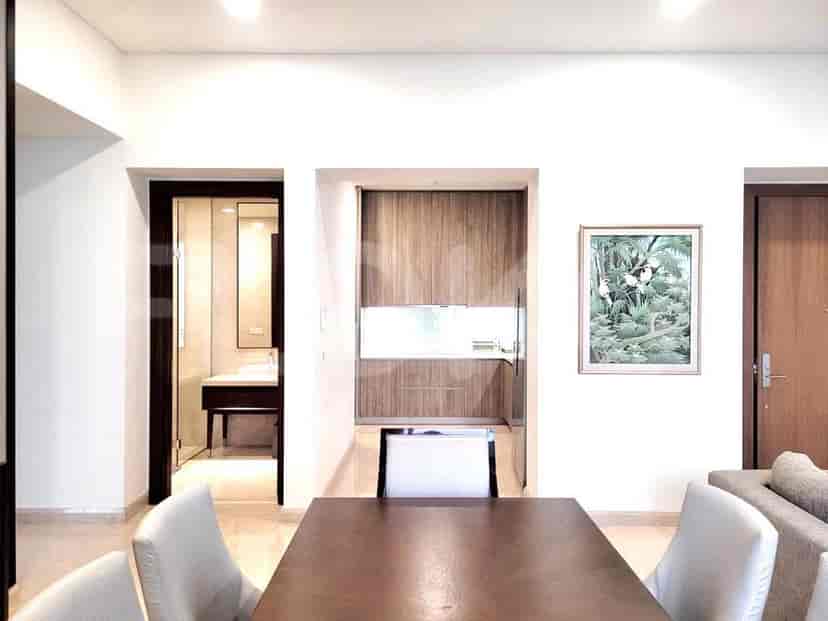 Area makan dengan meja, kursi, dan pintu masuk ke dapur dan kamar mandi.