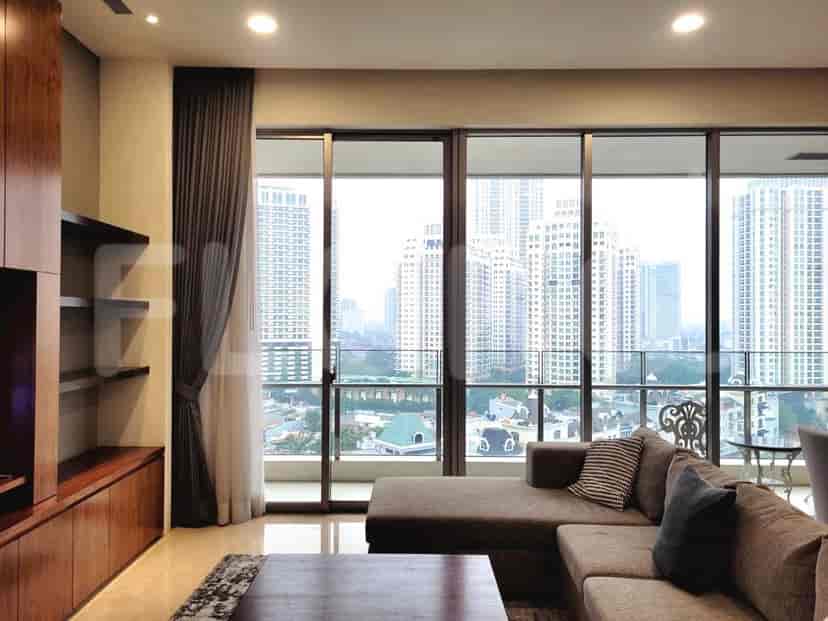 Ruang tamu dengan jendela besar yang menampilkan pemandangan kota, sofa, dan rak built-in.