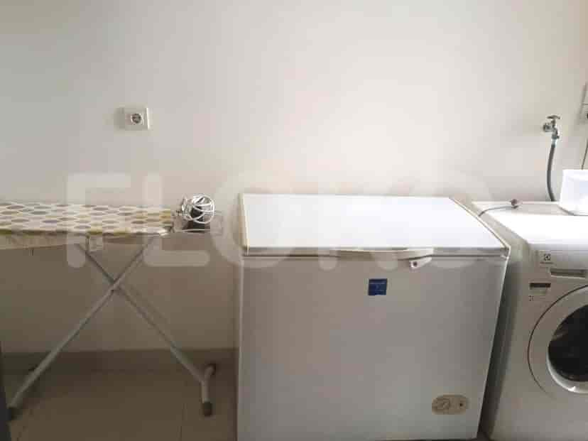 A laundry area with a washing machine, a freezer, and an ironing board.