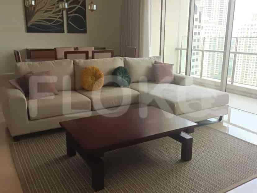 A bright living room with an L-shaped cream sofa, a dark wood coffee table, and access to a balcony with a city view.