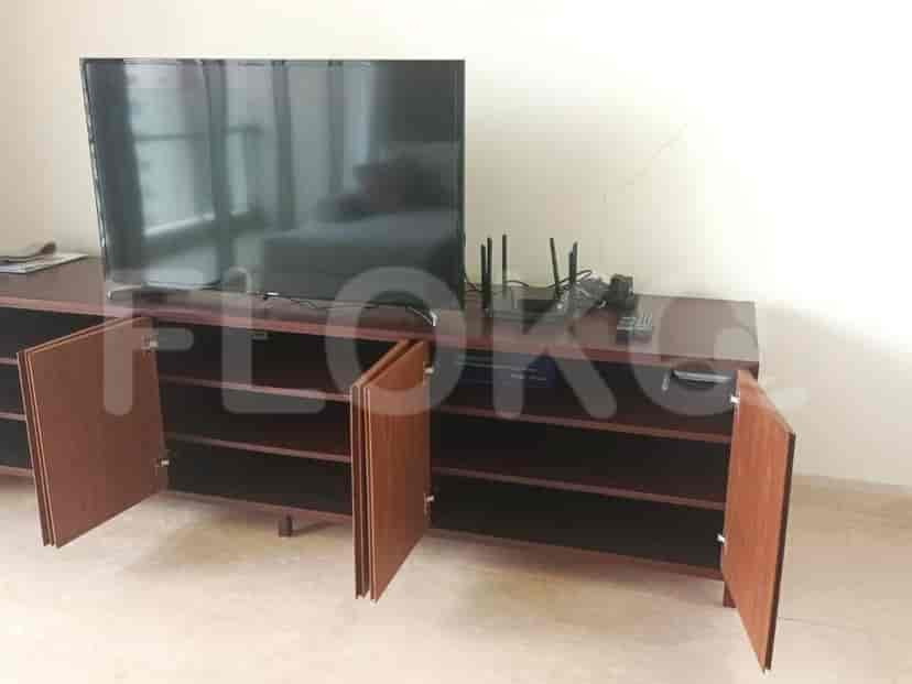 A long, dark wood entertainment unit with a large TV, a router, and visible storage cabinets.