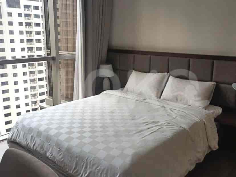 A well-lit bedroom with a bed, and nightstand next to a large window.