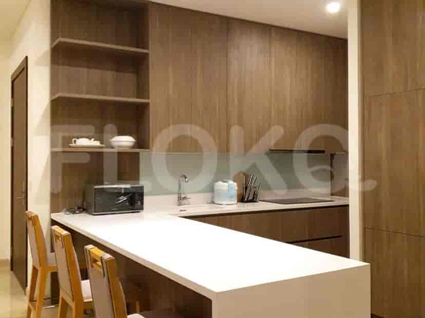 A modern kitchen with wooden cabinets, white countertops, and a breakfast bar.