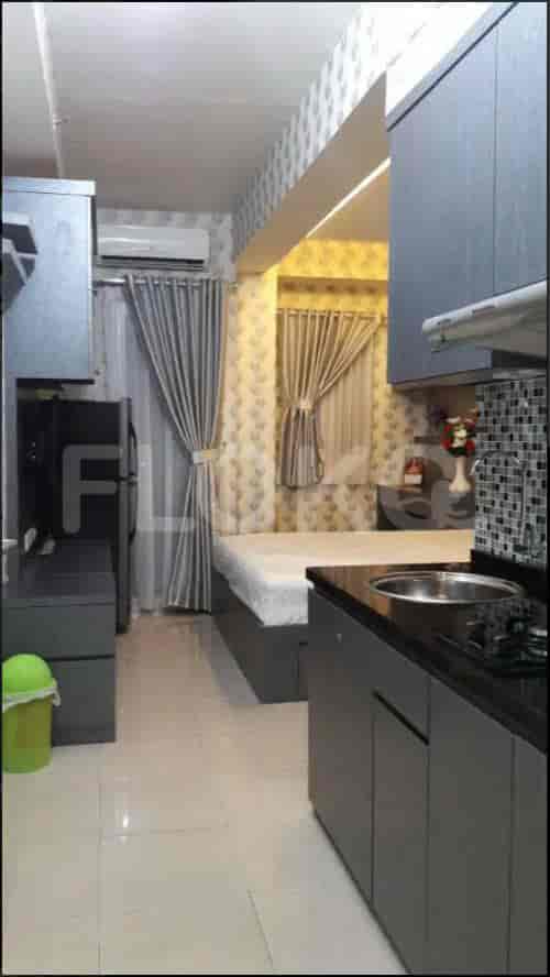 A small studio apartment layout with a bed, kitchen, and curtains.