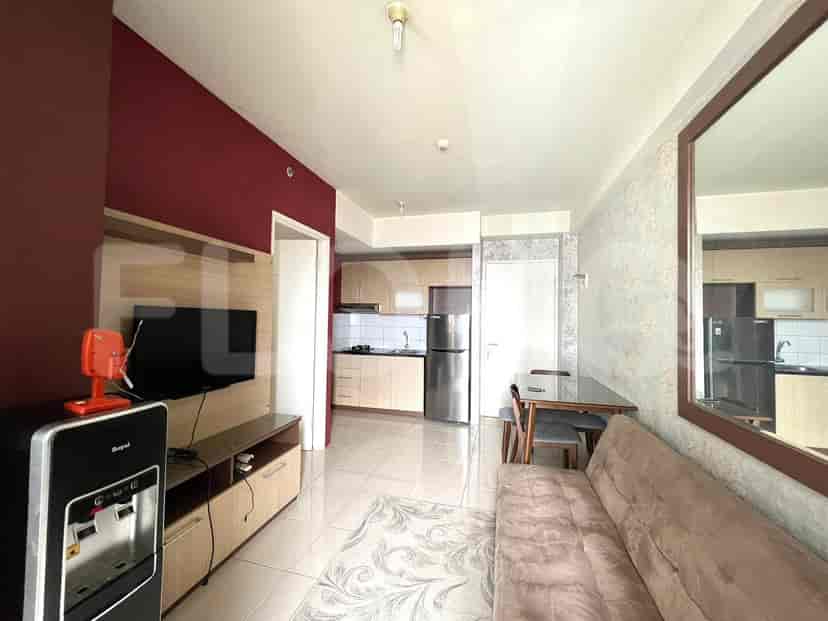 Compact living space with a TV, sofa, dining table, and an open kitchen.