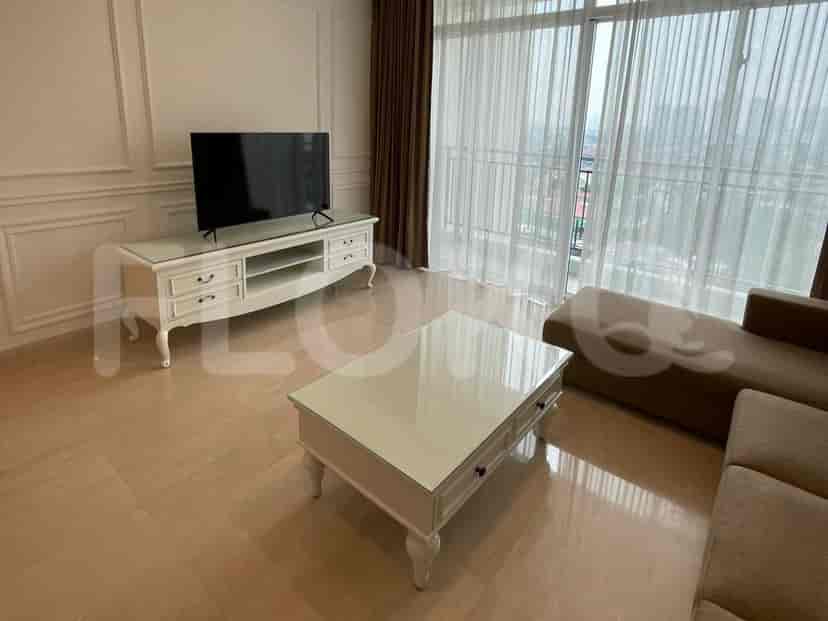 Living room showing a smart TV, coffee table, and sectional sofa near a balcony.