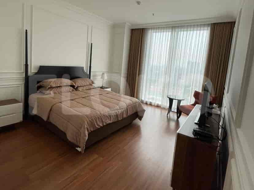 A bedroom with a king-sized bed, nightstand, and city view, with dark wooden flooring.