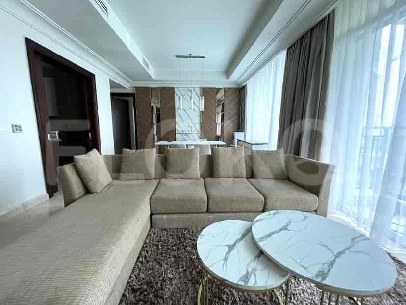 Ruang tamu yang luas dengan sofa berbentuk L berwarna krem, meja kopi marmer bergaya, dan pemandangan ke area makan.
