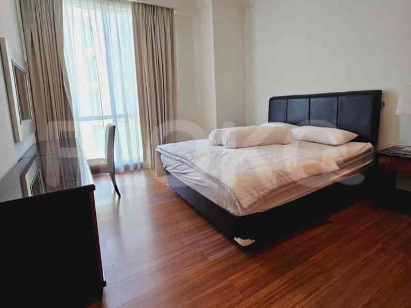 A bedroom with a double bed and large windows.