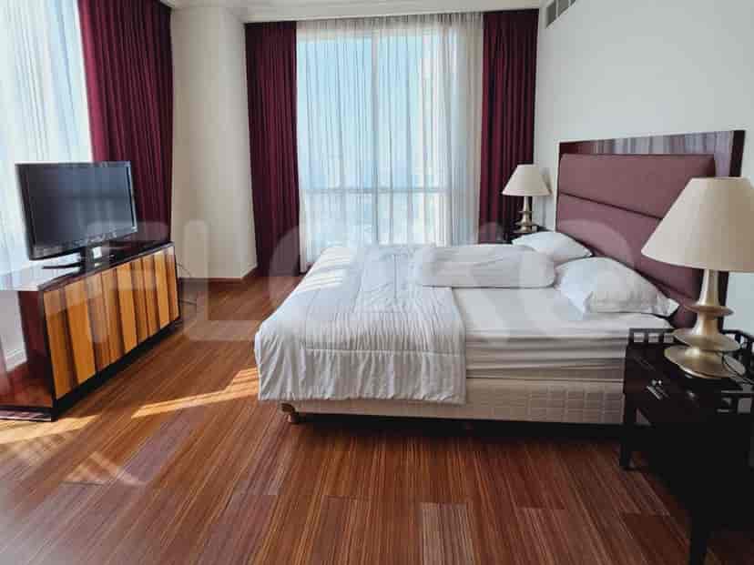 A luxurious bedroom with a large bed, TV, and dark wooden flooring.